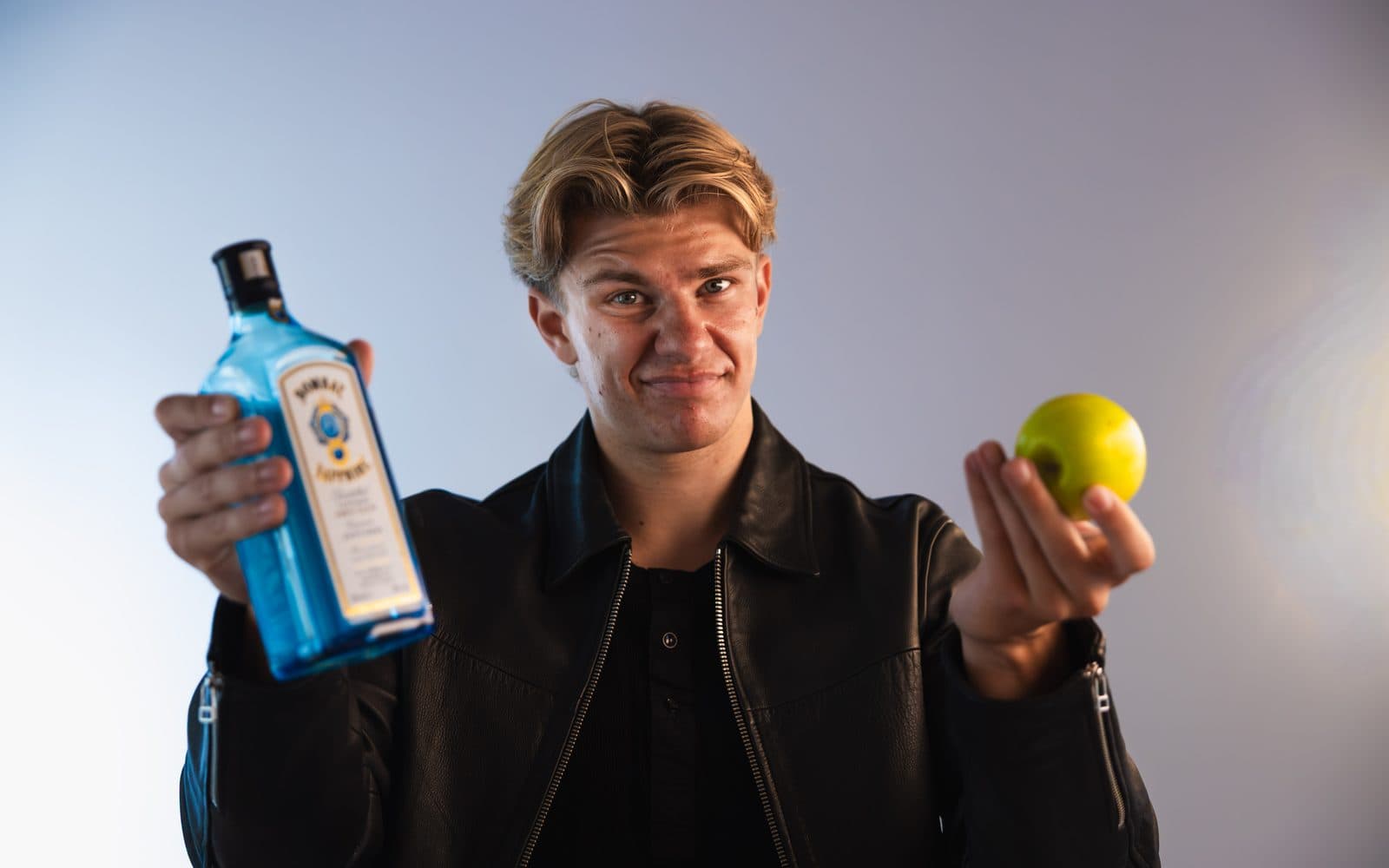 Elias Boisen Bonde holder en flaske gin i den ene hånd og et æble i den anden